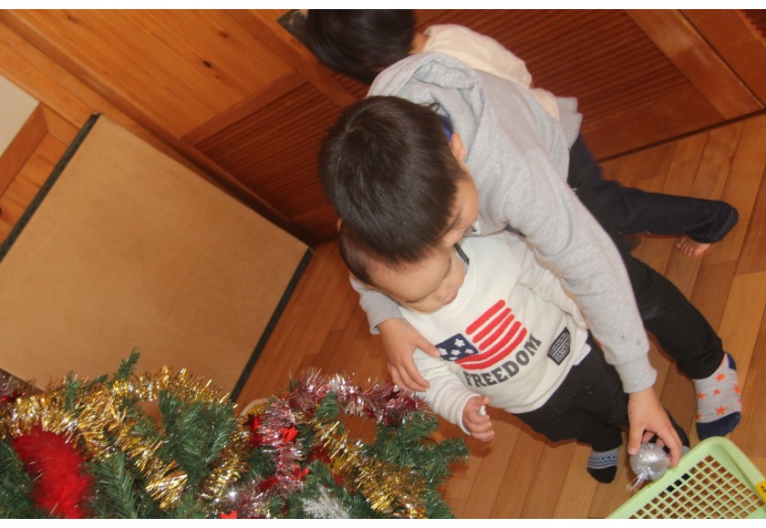 小さいお友達とクリスマスツリーの飾り付け。「どこにつける？」と優しいお兄ちゃんです。
